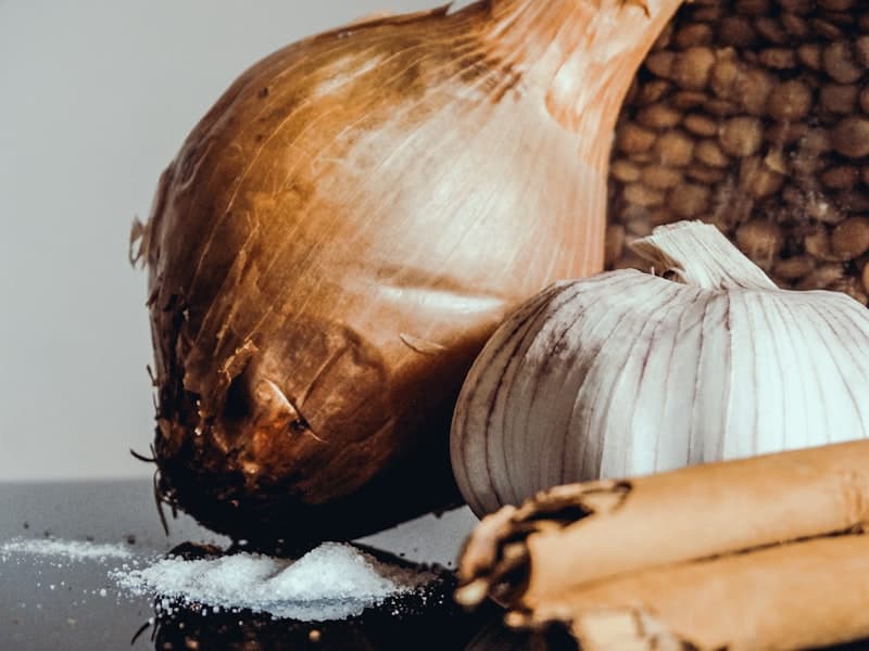 A bowl of fine red onion powder with whole onions in the background